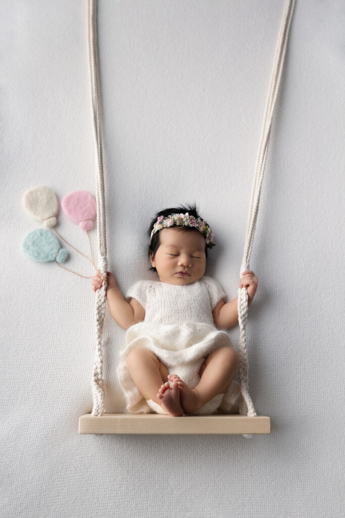 Newborn baby girl on swing prop - Belle Haven Photography