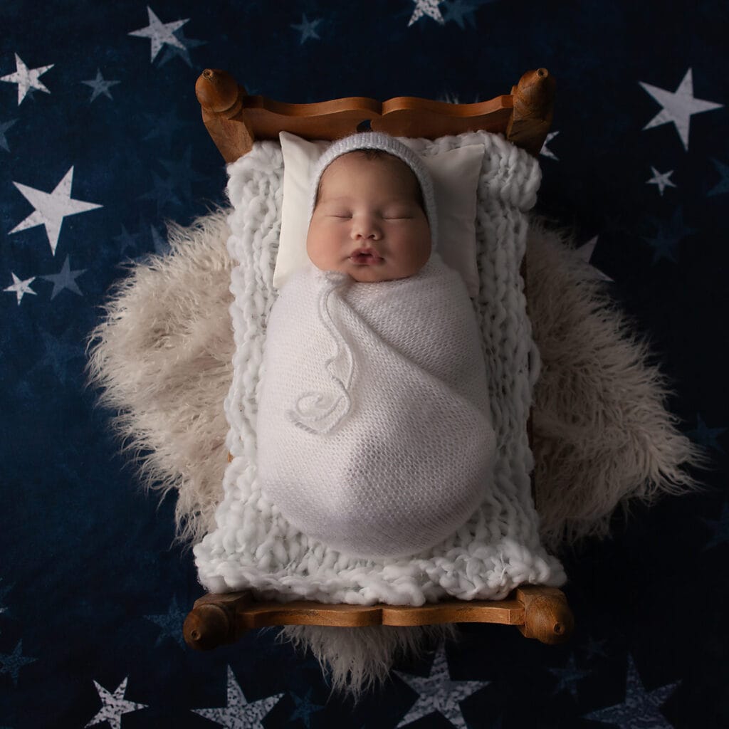 Newborn baby boy in a bed wrapped in white - Belle Haven Photography